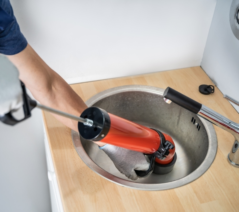 Plumber clearing a clogged kitchen sink drain in Odessa
