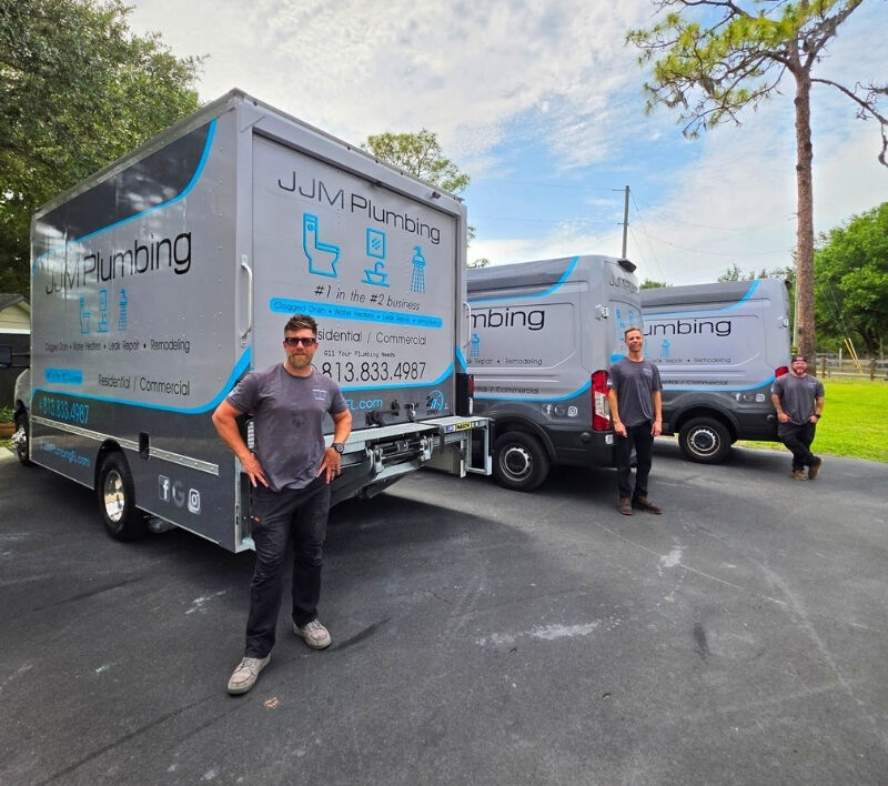 JJM Plumbing employees standing with their trucks